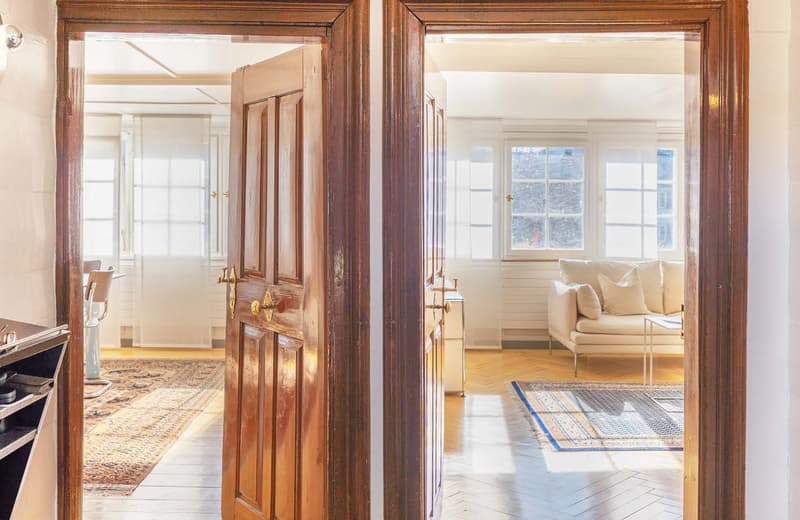 wooden door, wooden floor, white walls, white couch, white windows, rug, light