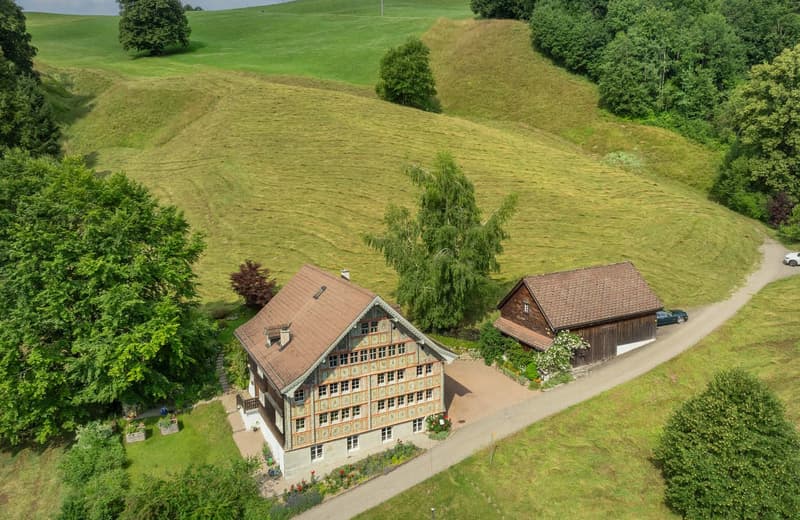 Large house in the middle of the hill, wooden barn in front