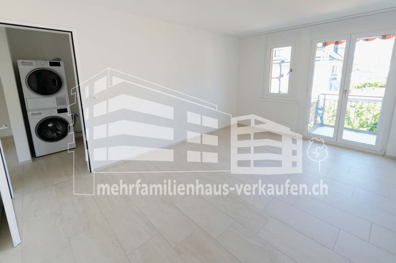 laundry area with washing machine and dryer, sliding door to balcony, minimalist white interior