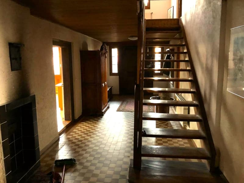 checkered floor, wooden staircase, fireplace, wooden cabinet, picture frames on the wall