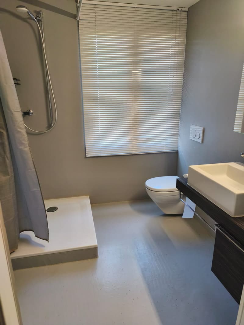 small bathroom with shower, toilet, sink, and window with blinds