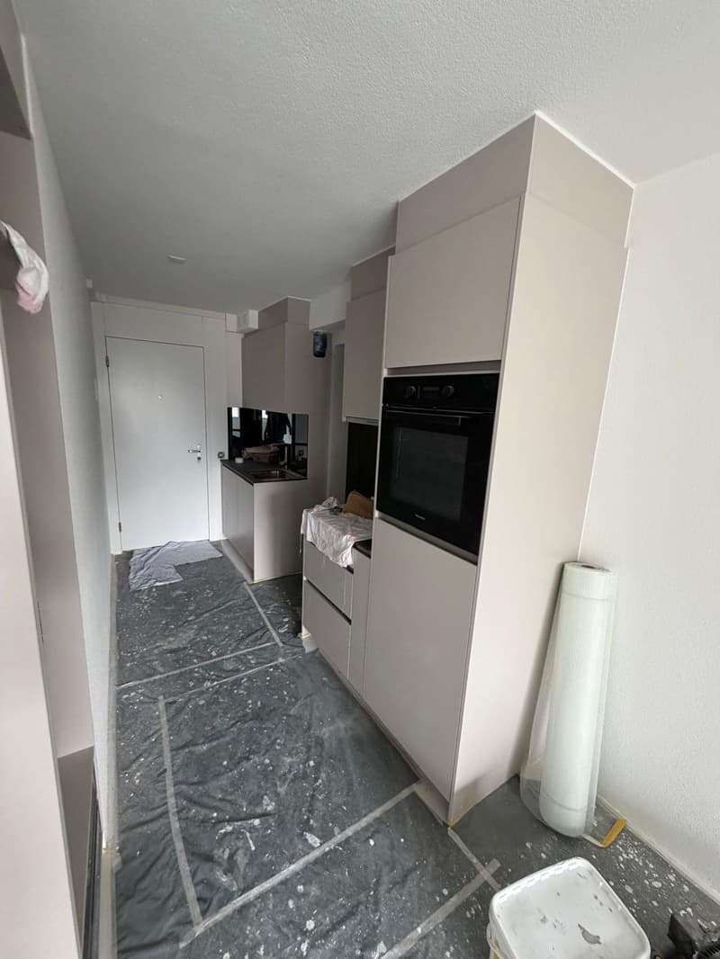 kitchen with white cabinets, black oven, sink, and countertop, grey floor, white walls