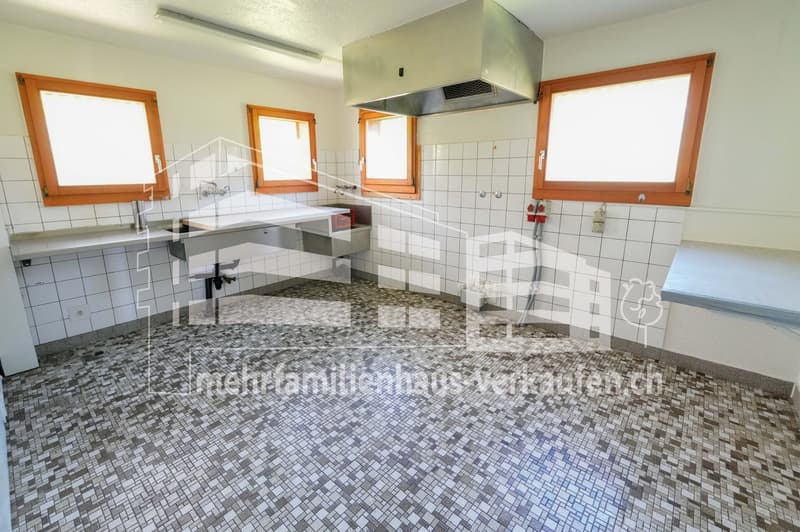 empty kitchen with tiled floor, two sinks, three windows, exhaust hood