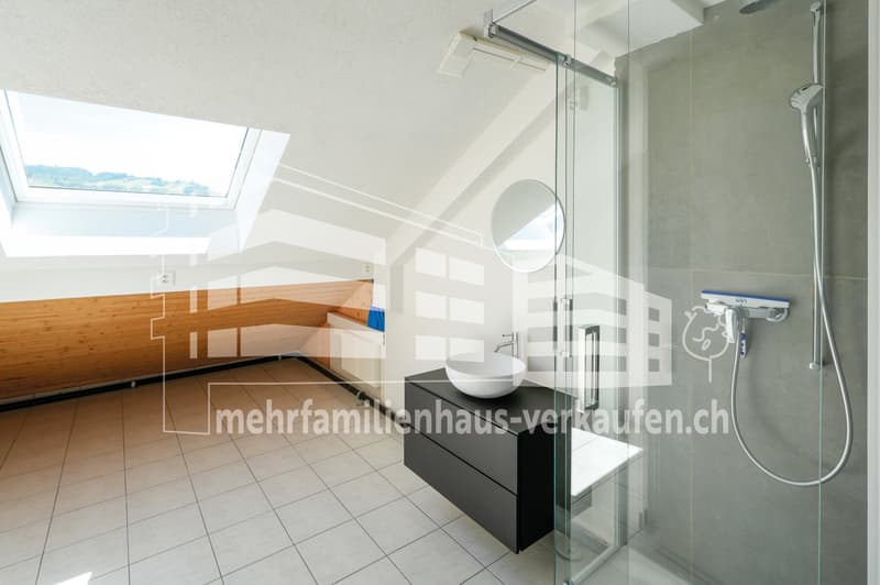 modern bathroom with glass shower, round mirror, white sink, black cabinet, white tiles, skylight