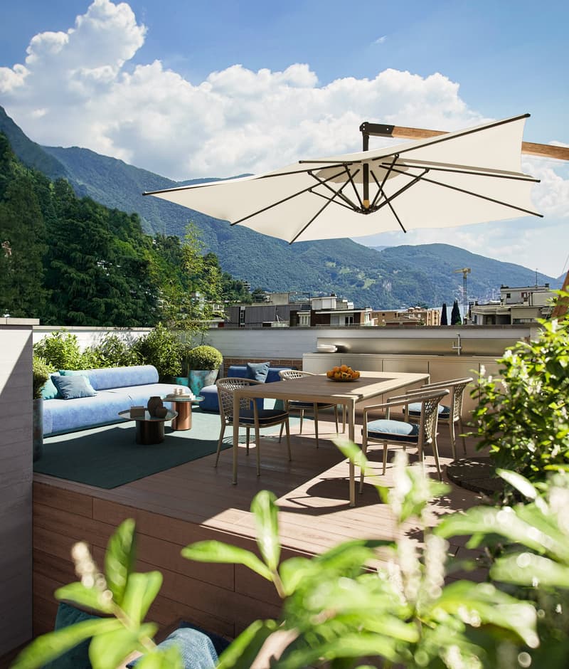An outdoor terrace with a dining table, chairs, sofa, umbrella, and beautiful mountain view