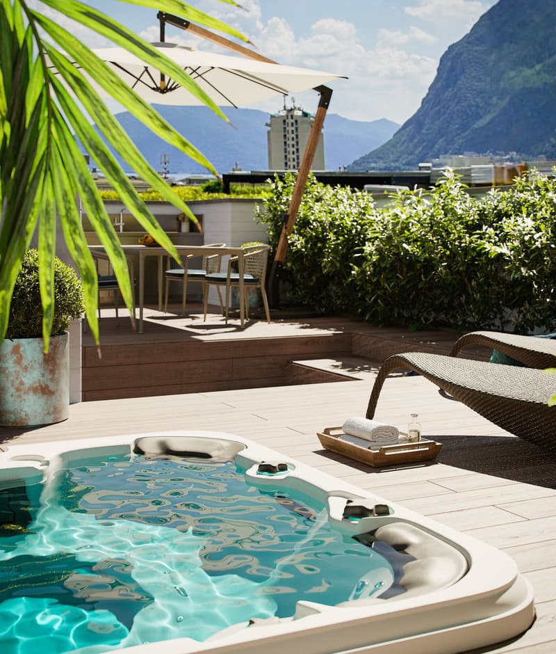 Decked area, outdoor spa, umbrella, tables and chairs, lounge chairs, plants, beautiful mountain view