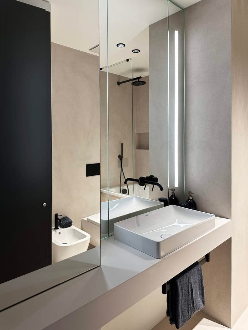 modern minimalist bathroom with large mirror, white countertop, and sleek bathroom fixtures, and a separate glass-walled shower