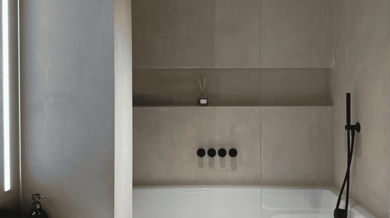 large white bathtub, shower head, three knobs, built-in shelves, neutral tone walls