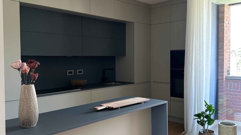 Modern kitchen with gray cabinets, countertop, large window, sink, flowers, potted plant