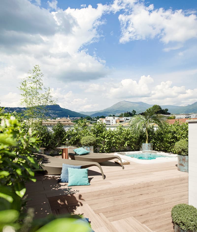 Terrace with deckchairs, pool, plants, mountains in the background