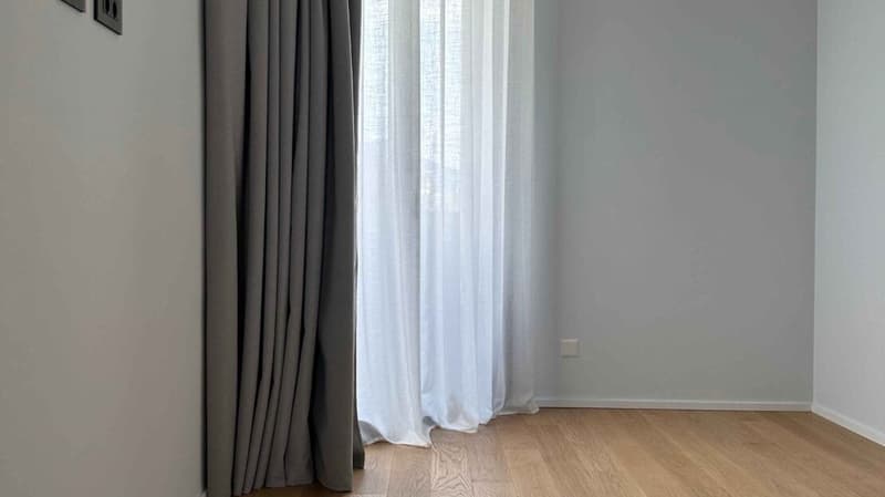 large window with white curtains, wooden floor, white wall, power outlet