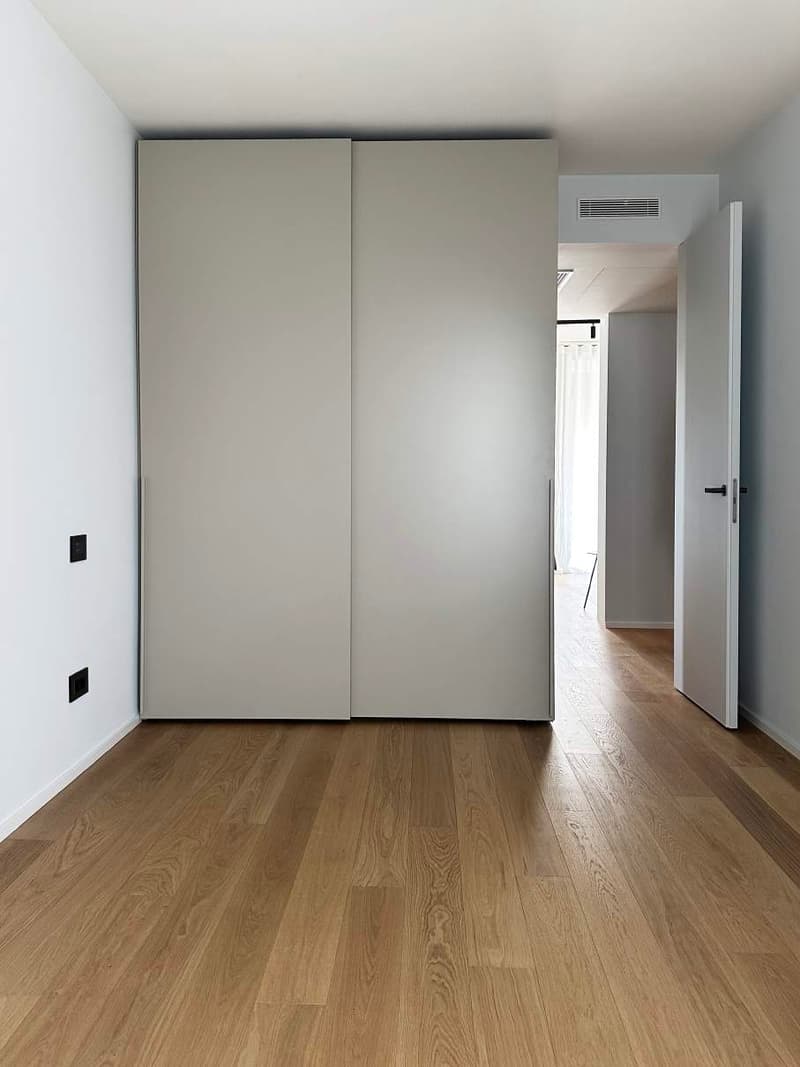 minimalist room, sliding doors, wooden floor, white walls, bright light from the corridor