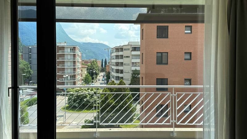 View of buildings and mountains from a balcony, balcony has railings