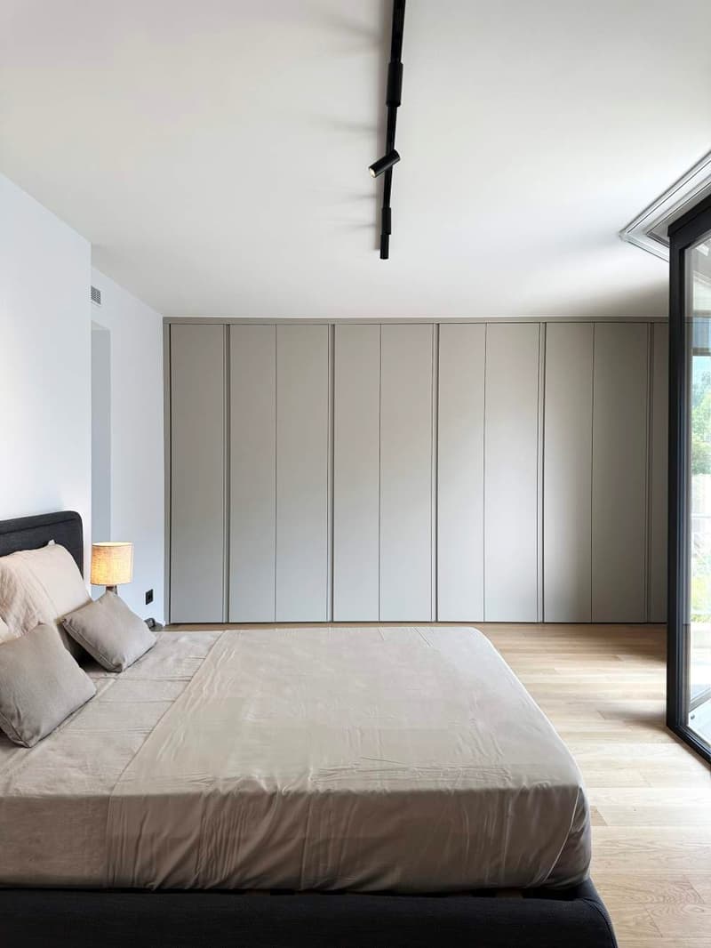 modern bedroom, double bed, grey cushions, lamp, large closets, wooden floor, white walls