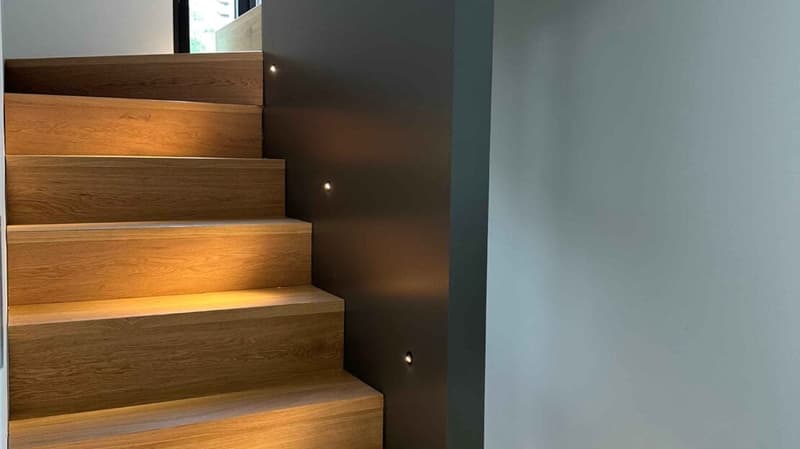 Modern wooden stairs with built-in LED lighting along the sides