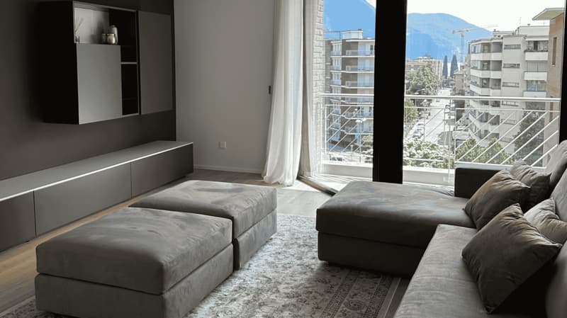 living room with couch, floor, wall shelves, large windows, balcony, city view
