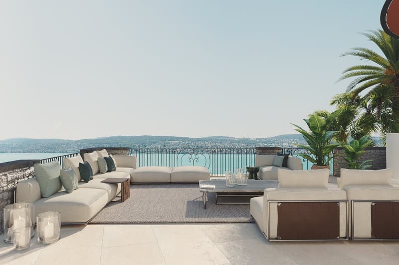 Outdoor living area with couches, center table, and decorative objects with a balcony overlooking water.