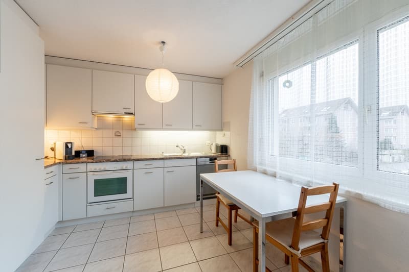 modern kitchen, white cabinets, tiled floor, kitchen island, oven, dishwasher, under-cabinet lighting, hanging lamp, coffee maker, toaster, microwave
