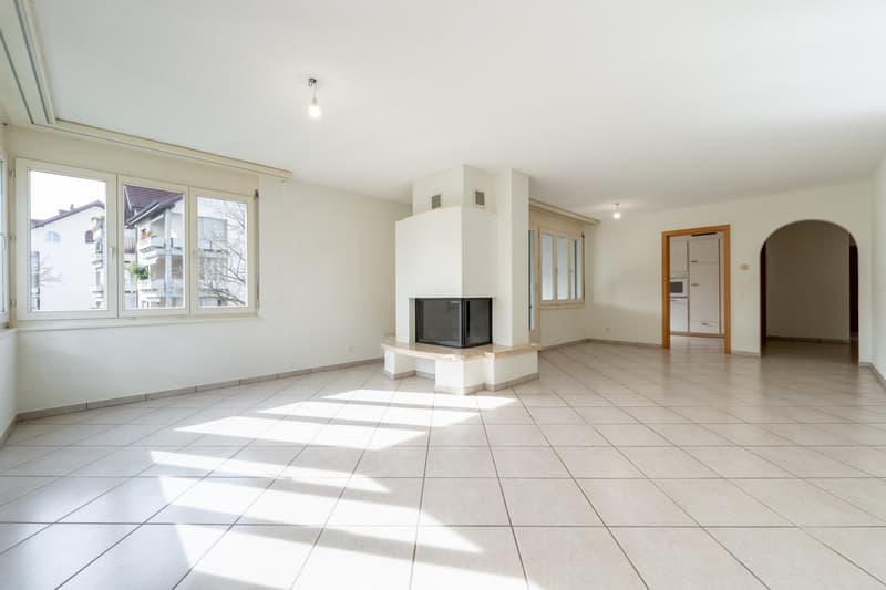 Empty room with fireplace, large windows, white walls, and tiled floor