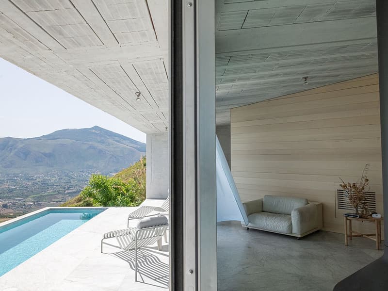 Modern interior, pool view, lounge chairs, couch, and side table with decorative items