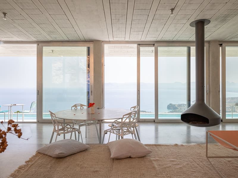 Open plan dining and living area, large sliding doors, round table, fireplace, ocean view