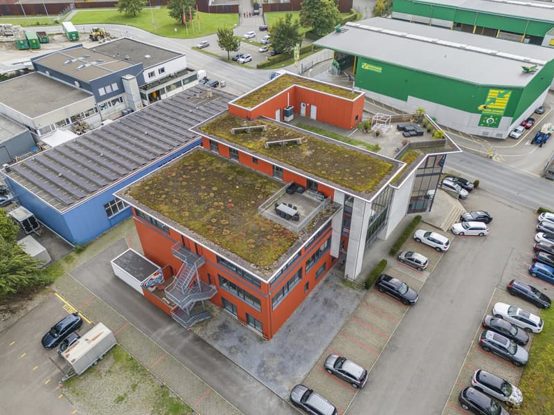 modern office building, rooftop garden, orange and green facade, solar panels, parking lot