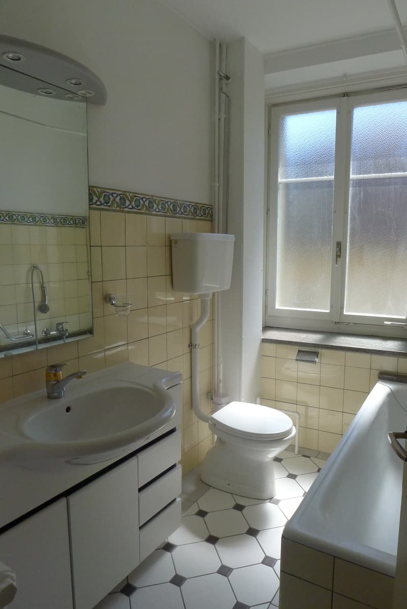 bathroom: white tiled floor, bathtub, toilet, sink, mirror, window, yellow tiles