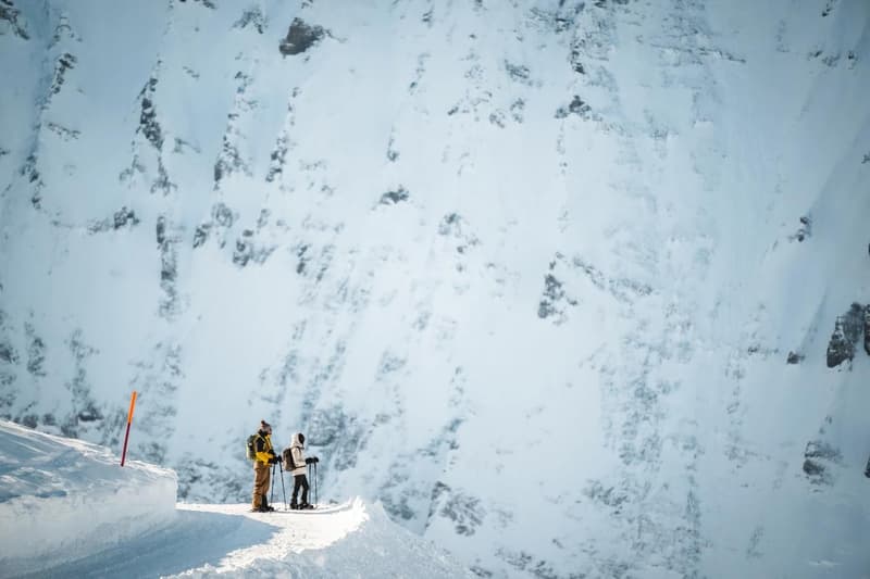 two skiers at the top of a snowy mountain, surrounded by snow and rock