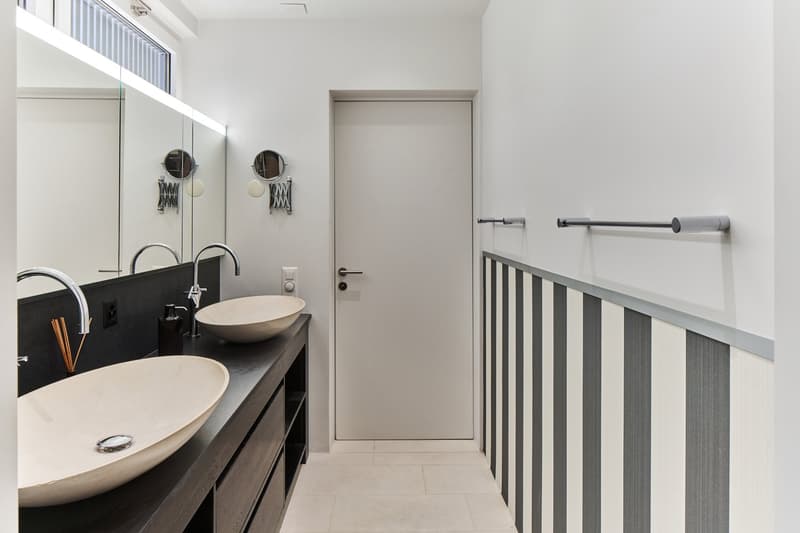 Modern bathroom with double vanity, vessel sinks, and a glass door leading to the hallway