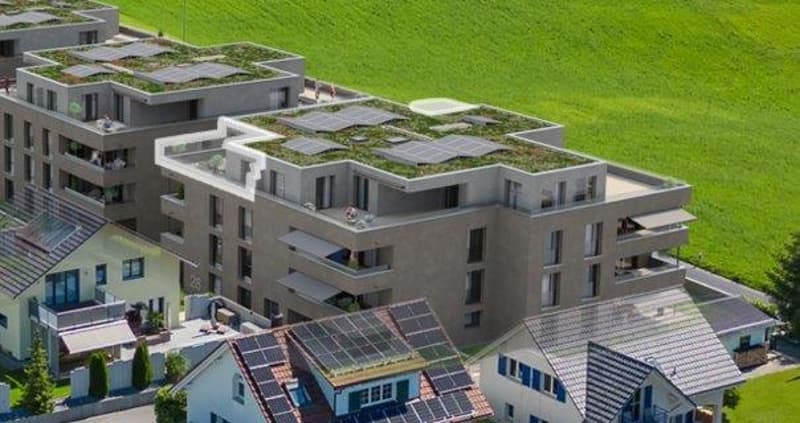 Aerial view of a modern apartment building with solar panels on the roof and balconies