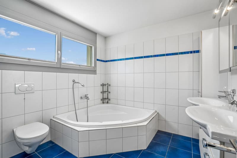 Geräumiges Badezimmer mit Eckbadewanne und Fenster.
