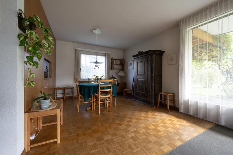 dining room with wooden floor, table and chairs, cabinets, stools, plants, window with curtains