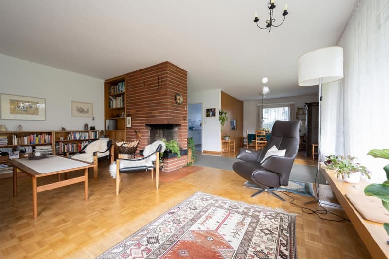 large living room with fireplace, bookshelves, coffee table, armchairs, rug