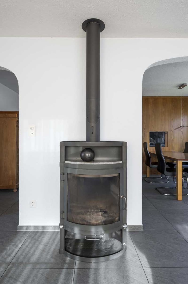 Fireplace with black round top, modern design, white wall, tiled floor, electrical outlets