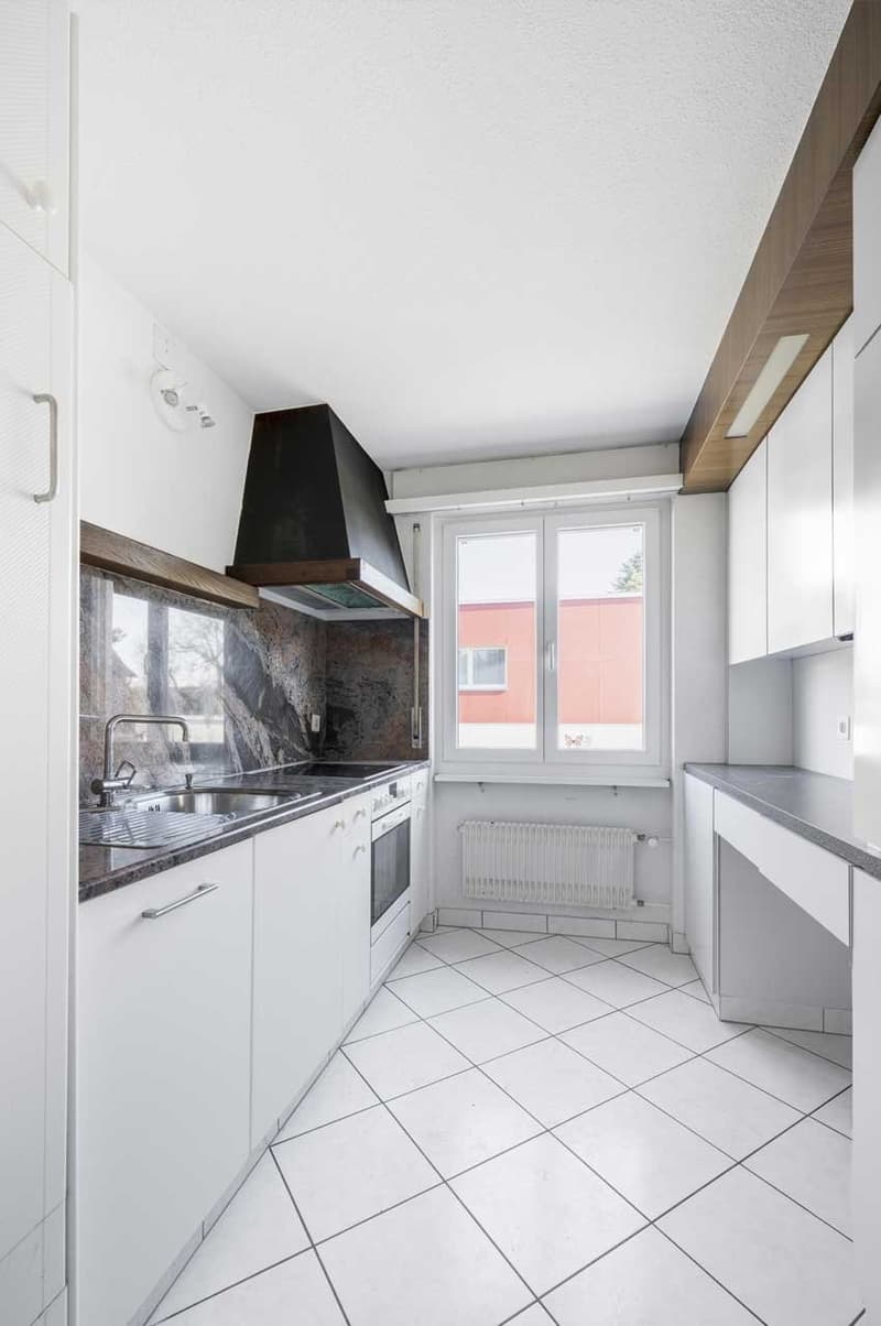 modern kitchen with white cabinets, tiled flooring, granite countertop, large window, black range hood, white sink