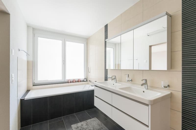 modern bathroom with bathtub, double sink, mirror, and tiled floor