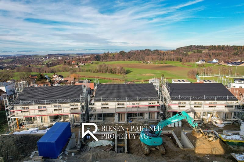 New houses under construction in rural area with green field in background