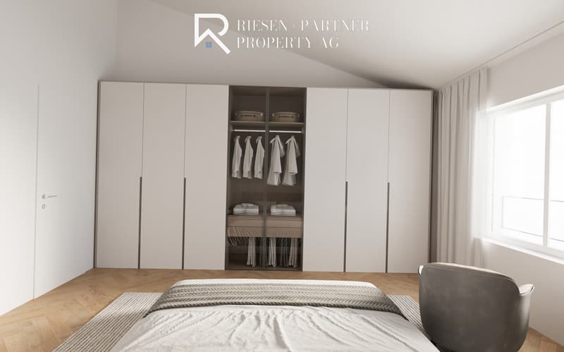 Modern bedroom with wooden floor, white walls, and white built-in wardrobe, large window with white curtains, single bed with gray and white duvet, gray armchair, and no visible appliances or features