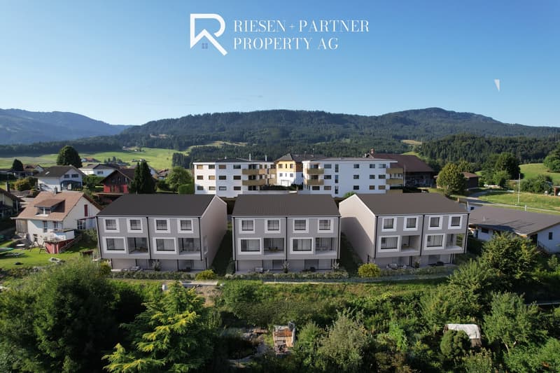 Multiple residential buildings, some with balconies, nestled among lush greenery and mountains