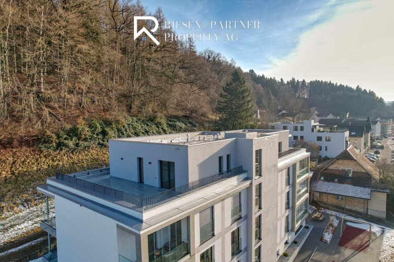 Modern apartment building, white exterior, large windows, multiple balconies, raised ground floor