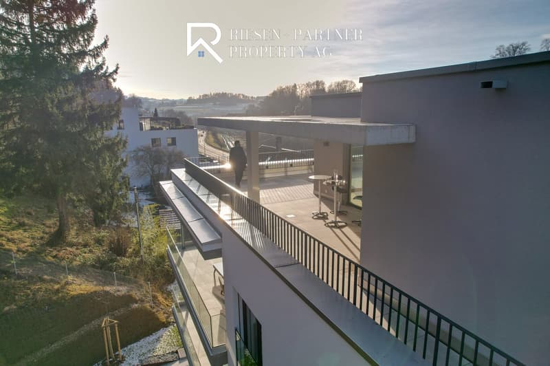 Contemporary two-story house, balcony with glass railing, metal railings on the terrace, scenic view