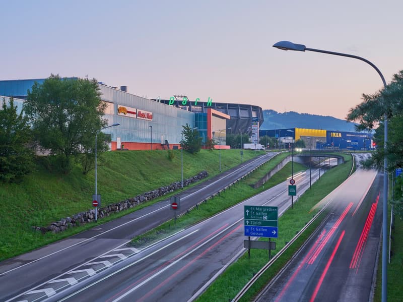 2-lane highway, concrete barrier, sign indicating St. Gallen Gossau and St. Margrethen Zentrum