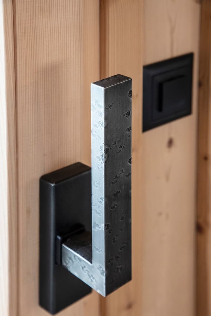 Black and silver door handle, wooden door, black square switch