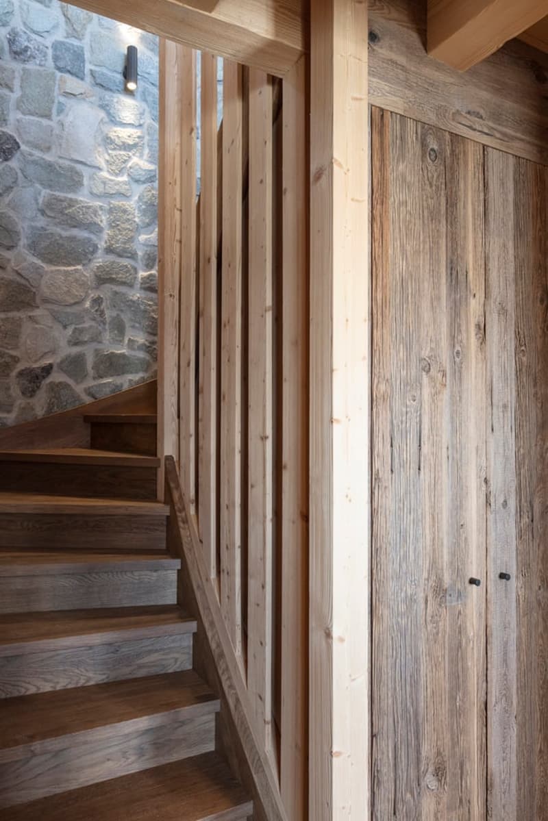 wooden staircase, wooden handrail, wooden wall, stone wall, wall light