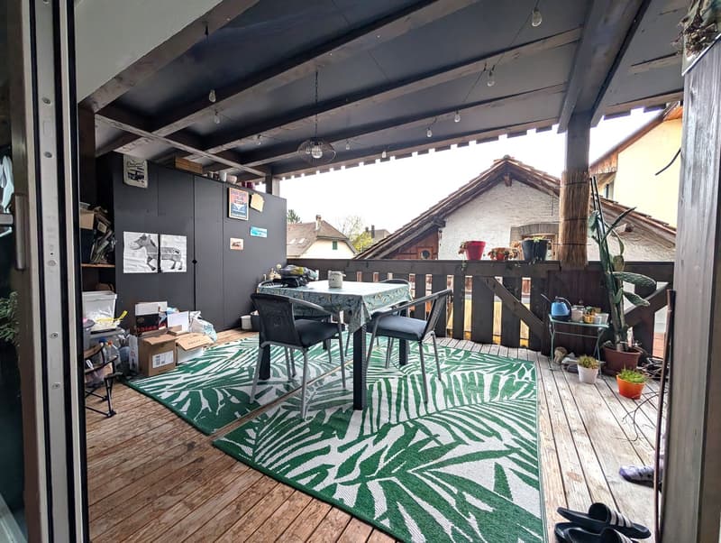 wooden floor, large rug, outdoor dining table, plants, string lights, open door
