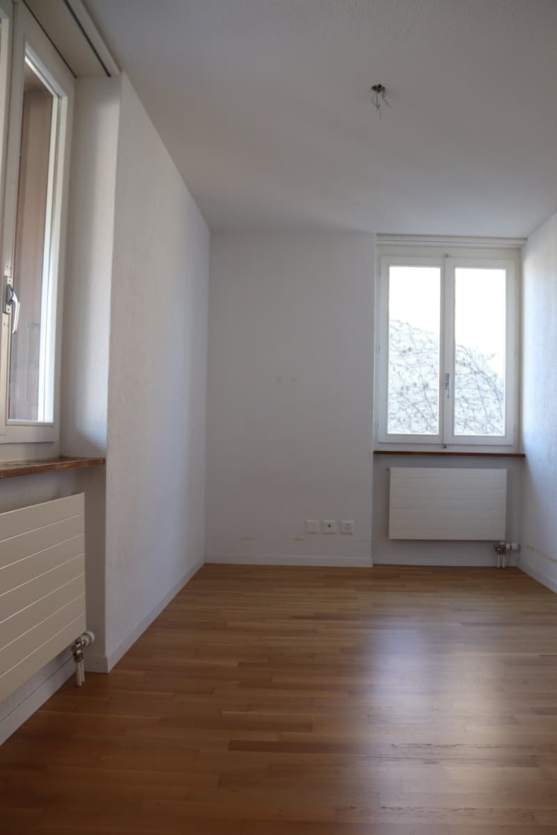 empty room, wooden floor, white walls, two windows, radiators