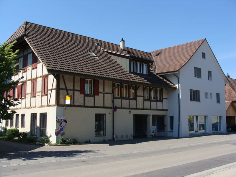 2 story house, brown roof, white and brown walls, multiple windows, red shutters, chimney, entrance with sign