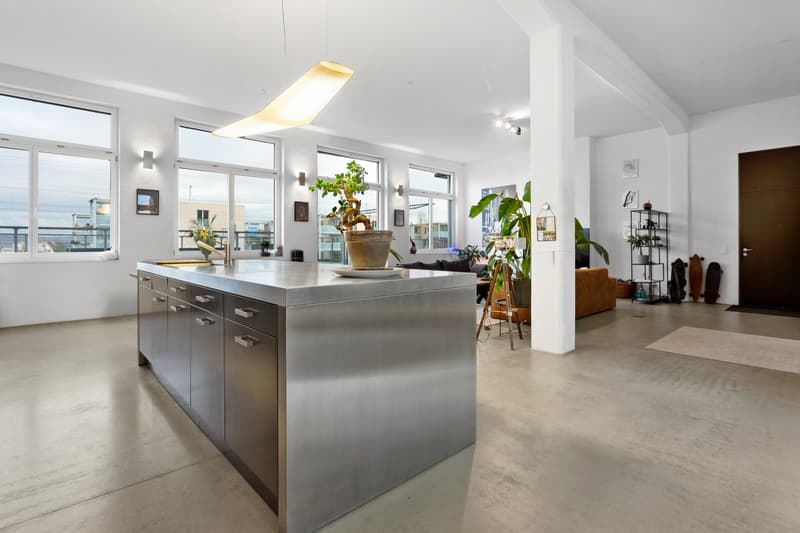 modern kitchen with stainless steel island, large windows, concrete floor, plants, modern lighting