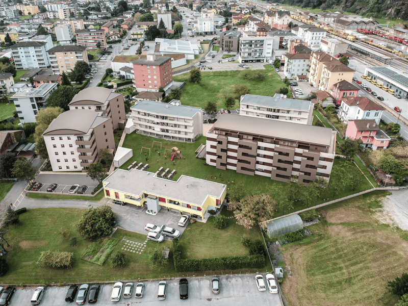complex of buildings, multiple parking lots, playground, wide view of city