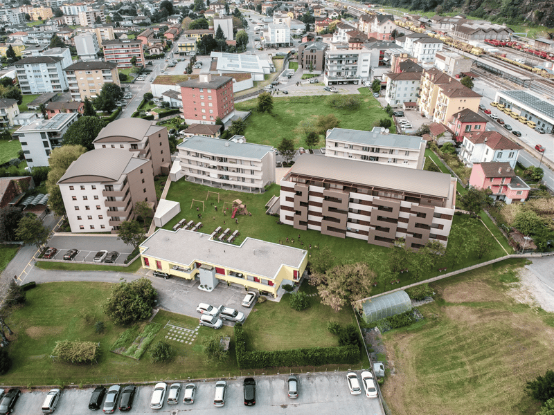 complex of buildings, multiple parking lots, playground, wide view of city